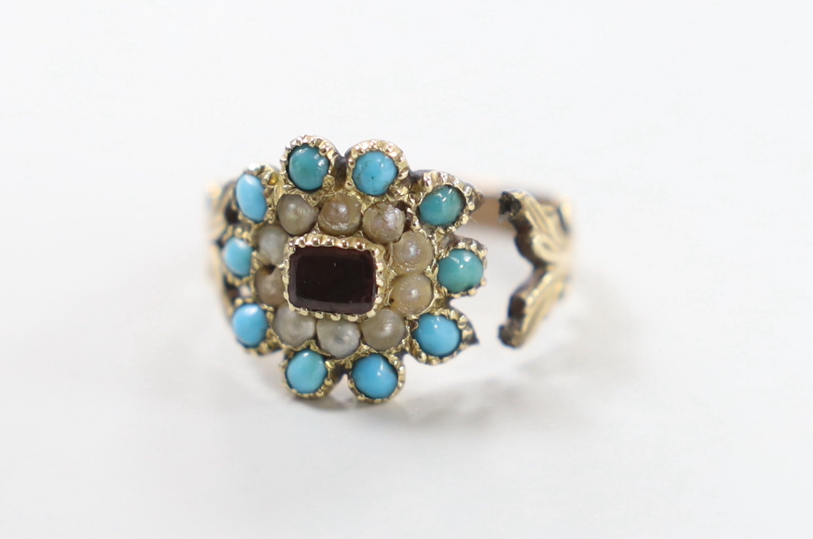 A Victorian yellow metal, foil backed garnet?, turquoise and seed pearl cluster set ring, (shank damaged), size M/N, gross weight 3.1 grams.